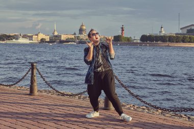 Genç adam Saint-Petersburg 'un arka planında dans ediyor. Kafkasyalı mutlu erkek turist.