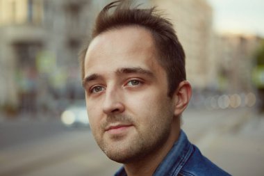 Şehirde yürüyen 27 yaşındaki genç, düşünceli, beyaz bir adamın portresi..