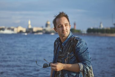 Rusya 'da Saint-Petersburg ve Neva nehrinin arka planında genç bir adamın portresi. Erkek 27 yaşında Avrupa seyahatinde..