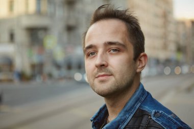 Gündüz vakti şehir sokaklarında yürürken genç ve çekici beyaz bir adamın portresi..