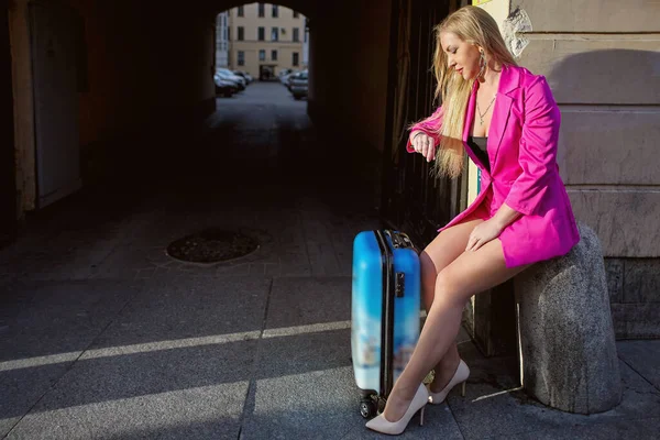 Жінка Дивиться Свій Годинник Чекаючи Таксі Сидячи Перед Багатоквартирним Будинком — стокове фото