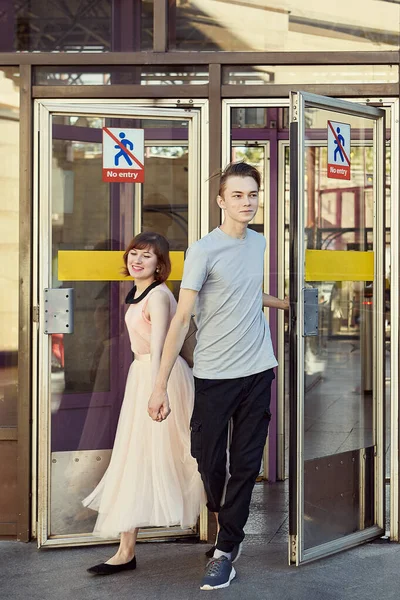 幸せな若い白いカップルは 地下鉄のドアを手を握って歩く 地下鉄の出口で20代の若者を笑顔に — ストック写真