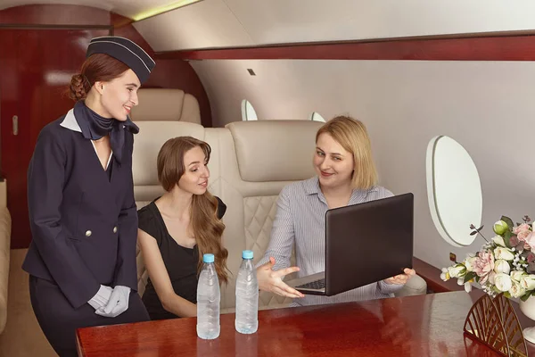 Passengers and air stewardess inside a corporate jet.