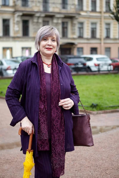 Een volwassen Europese vrouw wandelt in het centrum bij bewolkt weer. — Stockfoto