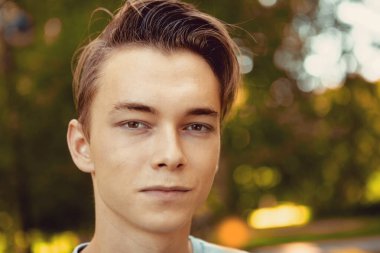 Yazın bir parkın arka planına yakın çekim yapan genç bir Rus 'un yüzü. Etrafı doğayla çevrili beyaz bir erkeğin portresi..