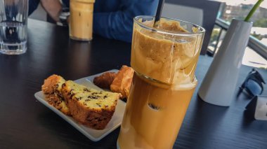 Buz Nescafe kahve siyah saman ile benzersiz cam fincan ve çikolata siyah ahşap masa üzerinde taze kurabiye yakın çekim