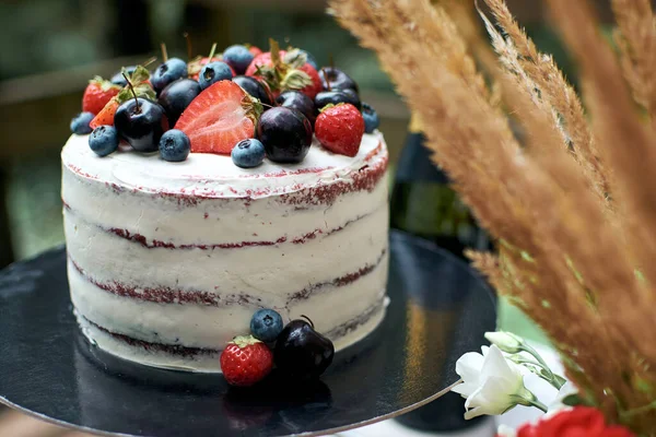 美味的裸体蛋糕加奶油奶油 蛋糕上装饰着新鲜的蓝莓 樱桃和草莓 侧视图 生日蛋糕为庆祝生日或婚礼准备的薄饼 图库照片