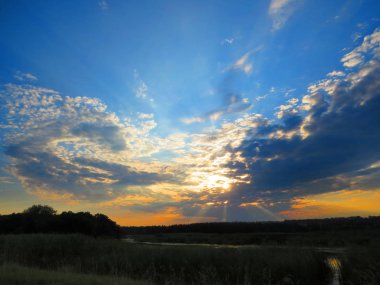 Göletüzerinde güzel gün batımı, güneş ışınları bulutların arasından yol yapmak