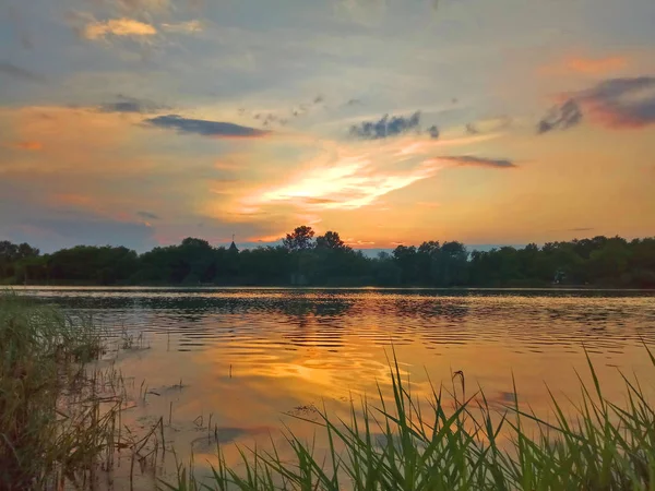 Güzel stratus ve cirrus bulutlar gölet üzerinde gün batımı ile aydınlatılmış