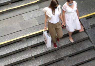 Paketli kadınlar metrodaki merdivenlerden aşağı iniyor.