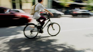 Hareket gücü bulanıklaştı, bir bisikletçi cadde boyunca arabaların yanında hareket ediyor.
