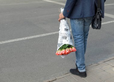 Sokakta elinde çiçek buketi olan bir adam.