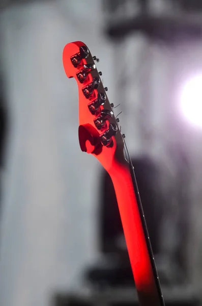 electric guitar stands on the stage in the rays of red spotlights before the concert on a dark background. concept of music and rock festival
