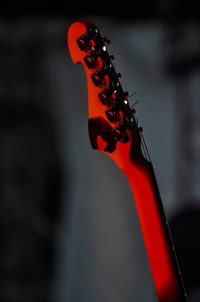 electric guitar stands on the stage in the rays of red spotlights before the concert on a dark background. concept of music and rock festival