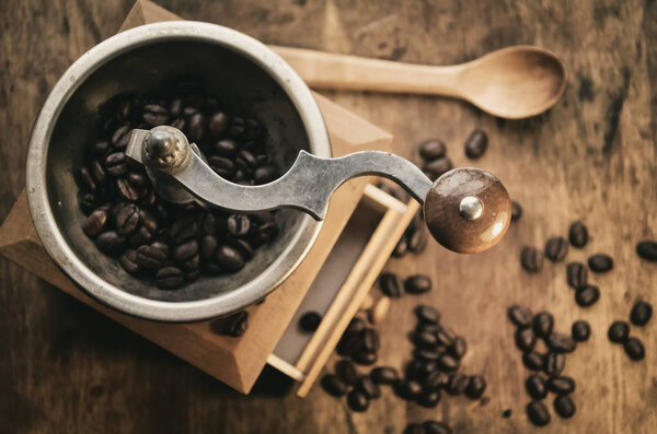 Old vintage coffee grinder with grains of coffee on a wooden table. retro style.  Copy-space. selective focus.