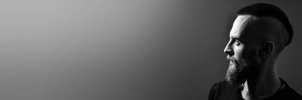 banner with free copy space for text. portrait. Profile of a young man with a red beard on a gray background. Mohawk hairstyle, iroquois, mohican.