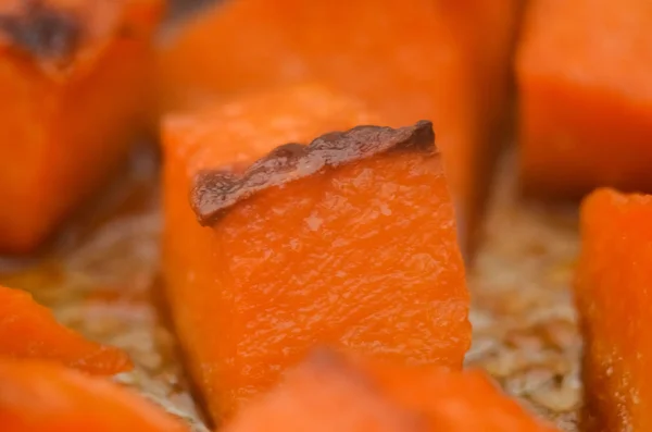 Pieces of sweet pumpkin baked with sugar for Halloween dinner. Healthy Vegetarian food. Autumn warm dish as a dessert. Selective focus, close-up. copy space.