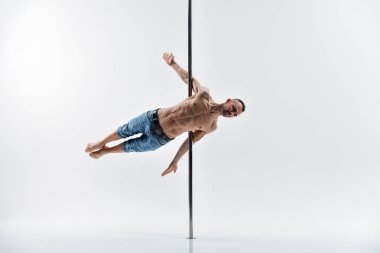 Genç direk dansı atleti beyaz arka planda numara yapıyor. Kaslı beyaz erkek sporcu direk dansı yapıyor.. 