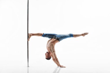 Genç direk dansı atleti beyaz arka planda numara yapıyor. Kaslı beyaz erkek sporcu direk dansı yapıyor. Esnek ve güçlü fitness modeli. 