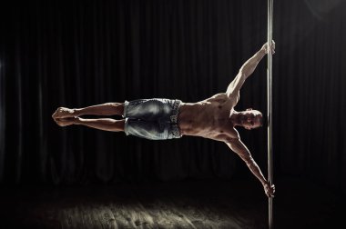 Pole dans erkek atlet. Güçlü ve kaslı adam bir hüner yürütür. Pole dans dünya şampiyonu becerileri gösteren. 