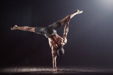 Handstand kas atlet. Genç adam siyah arka planda kamera karşı karşıya iki el üzerinde denge yapıyor. Fitness adam pratik handbalance. 