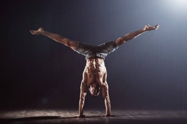 Handstand kas atlet. Genç adam siyah arka planda kamera karşı karşıya iki el üzerinde denge yapıyor. Fitness adam pratik handbalance. 