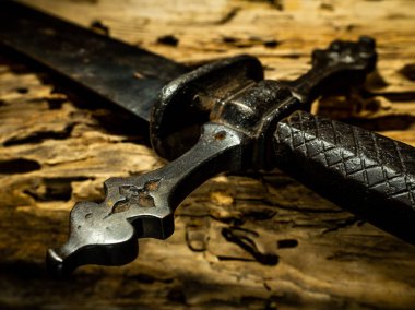 Ayrıntı ortaçağ kılıç kolu ve ahşap arka plan tetikte