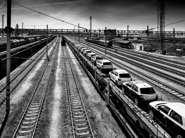 Nieuwe auto's op een lange trein in een treinstation in zwart en whit — Stockfoto