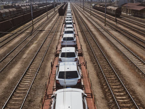 Νέα αυτοκίνητα επάνω έναs μακρύς τρένο σε ένα σιδηροδρομικό σταθμό — Φωτογραφία Αρχείου
