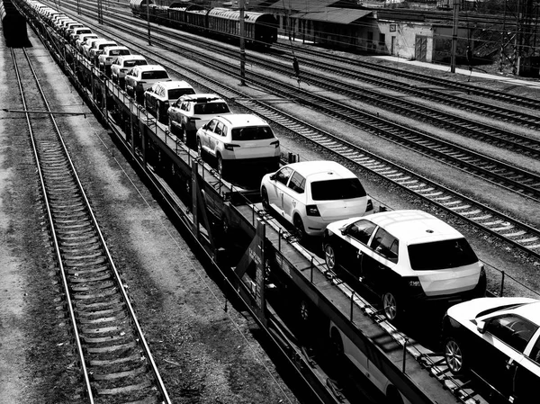 Νέα αυτοκίνητα επάνω έναs μακρύς τρένο σε ένα σιδηροδρομικό σταθμό σε μαύρο και της Πεντηκοστής — Φωτογραφία Αρχείου