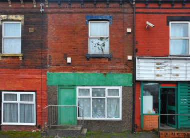 eskiyen renkli boyalı duvarlar ve açık bir kapı ile bir dükkan ön ile leeds bir sokakta teraslı evler aşağı çalıştırmak
