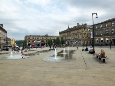 Huddersfield Yorkshire'daki St. George Meydanı'ndaki çeşmelerde oynayan aileler ve çocuklar