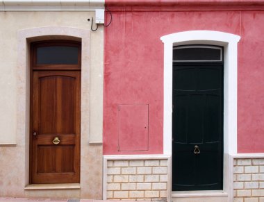 pembe ve beyaz boyalı konut eski evlerde yan yana iki komşu farklı renkli ön kapılar