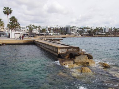 palmiye ağaçları ve iskele ile gezinti boyunca daire ve beyaz otel binaları ile baf Kıbrıs sahil