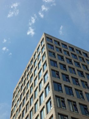 pencerelere yansıyan güneş ışığı ve mavi güneşli gökyüzü ile beyaz yüksek beyaz beton binaların dikey açılı köşe görünümü
