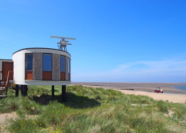 fleetwood eski acımasız sahil güvenlik istasyonu ve mavi gökyüzü ile parlak güneş ışığı altında bir yaz gününde plaja giden kaba kaplı kumulları ile radar antenleri ile