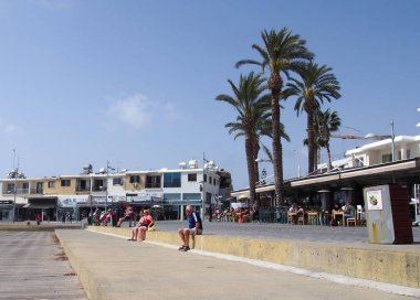 Baf, Kıbrıs - 15 Mart 2018: Kıbrıs'ın Baf kasabasında ki gezinti duvarının duvarında deniz kenarındaki restoranlarda yemek yiyen lerle turistler oturdu