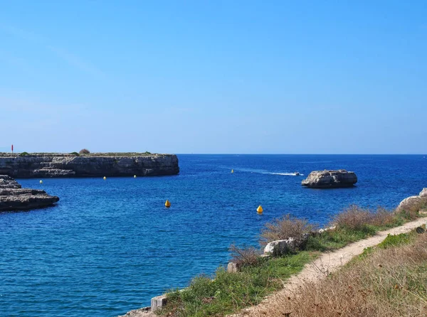 ciutadella calla Des Degeledor bir manzara mavi güneşli deniz ve mesafe bir sürat teknesi ile koya bakan bir uçurum yolu ile