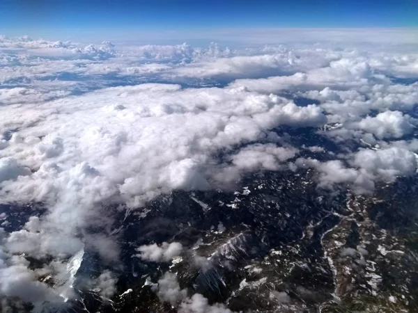 地平線と青空に見える地球の曲率を持つ緑の丘や山々に見える雪で雲に覆われた山の風景の航空写真 — ストック写真
