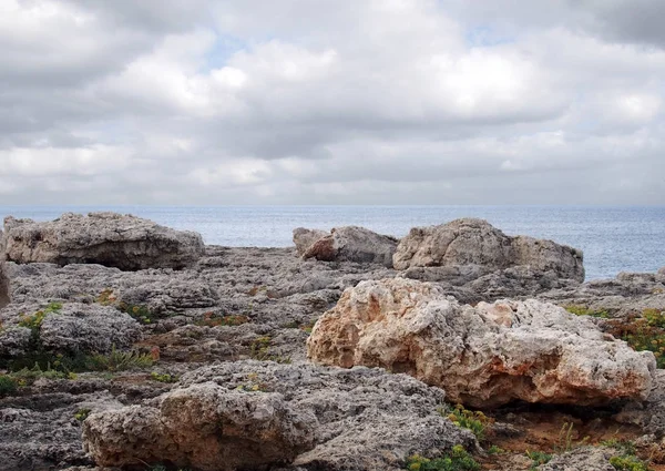 menorca İspanya seyahat veya tatil arka plan ve beyaz bulutlar ile bir denize karşı engebeli kıyı kayalar