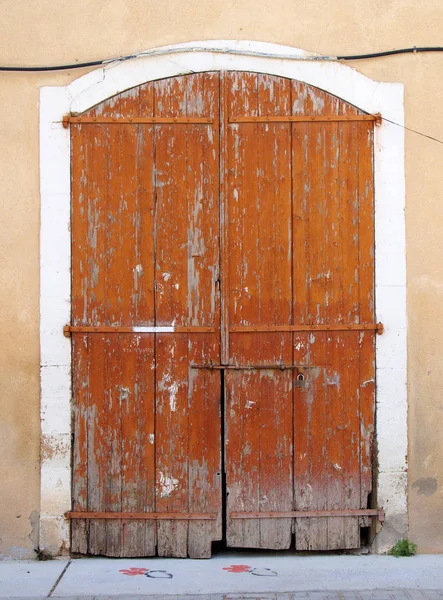 古い絵のように腐敗した茶色の塗装された木製の二重ドアは 通りに色あせたピンクのコンクリートの壁に白い石のフレームに設定された南京錠で閉じました — ストック写真