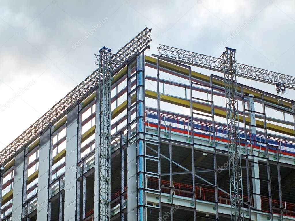 a large modern building site with construction scaffolding and steel girder framework with safety fences
