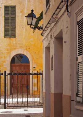 panjur ve bir sokak lambası ile bir çit arkasında eski kapı ile ciutadella menorca güneşli bir caddenin köşesinde