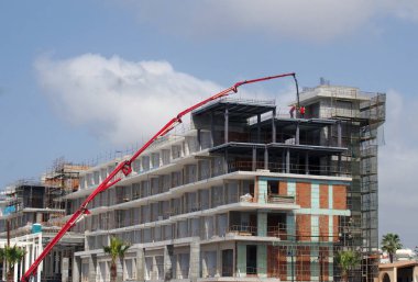büyük kırmızı teleskopik vinç ve inşaat işçileri kıbrıs büyük bir modern otel kompleksi bina ile şantiye