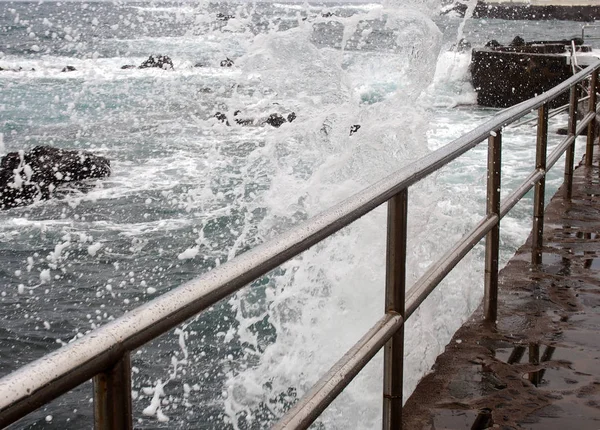 Altas olas dramáticas rompiendo sobre un paseo marítimo con el mar —  Fotos de Stock