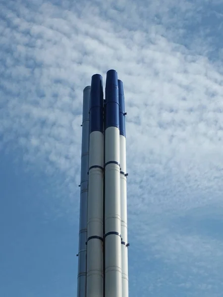 Eine Gruppe hoher moderner Industrieschornsteine aus Stahl, die vor einem strahlend blauen Himmel und weißen Wolken stehen — Stockfoto