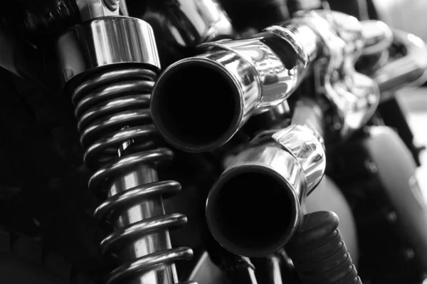 Close up rear view of a powerful classic black vintage motorcycle showing suspension and shiny chrome exhaust pipes — Stock Photo, Image