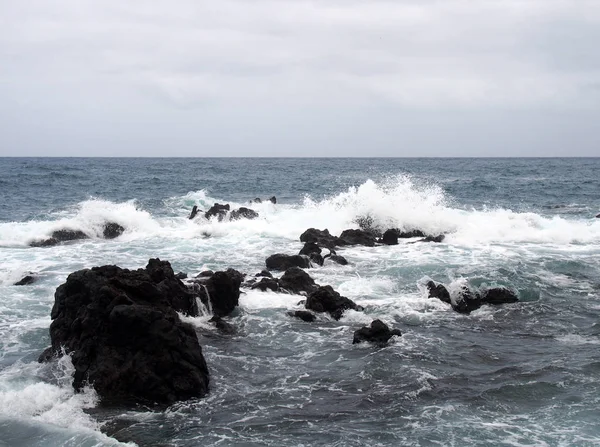 海景与风暴的巨浪打破沿海岩石与白色的冲浪和灰色的天空 — 图库照片