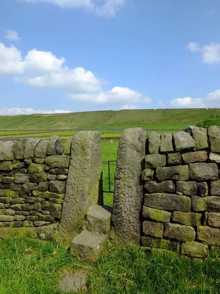 Parlak mavi yaz gökyüzü ve güneşli çim ile yorkshire dales yamaç çayır adımları ile taş stile veya dar kapı ile kuru bir taş duvar — Stok fotoğraf