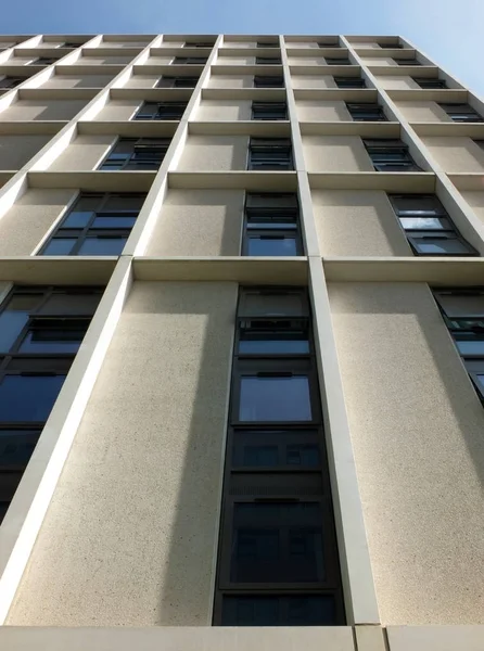 Vertical view of a tall concrete angular modern high building with geometric white details against a blue sky Stock Picture